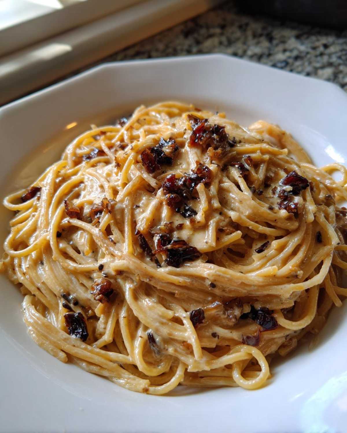 Close-up of creamy caramelized onion pasta tossed with rich sauce and topped with dark caramelized onions.