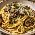 Close-up of creamy mushroom pasta tossed with linguine, topped with sautéed mushrooms, Parmesan, and fresh parsley.