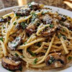 A close-up shot of creamy mushroom pasta tossed in a white sauce, topped with sautéed mushrooms, fresh parsley, and grated Parmesan cheese.