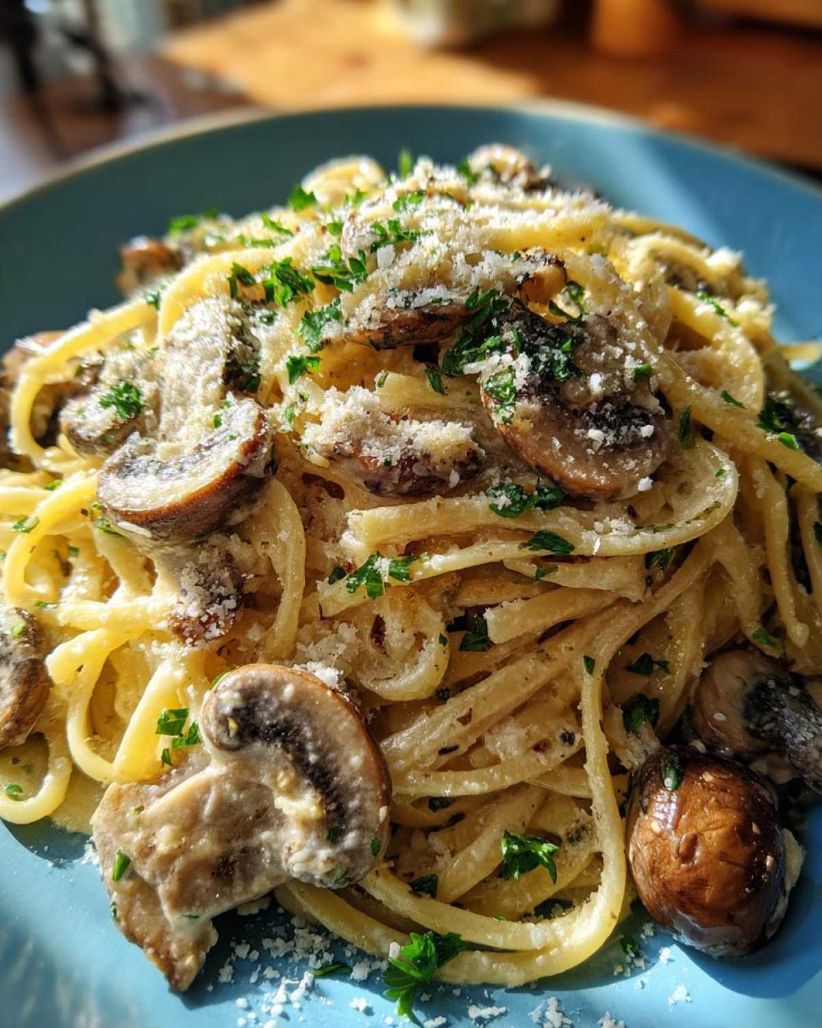 A close-up serving of creamy mushroom pasta, topped generously with sliced mushrooms, grated Parmesan, and fresh parsley.
