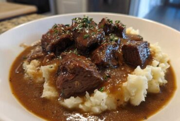 Close-up of tender crockpot beef tips smothered in rich brown gravy served over creamy mashed potatoes.