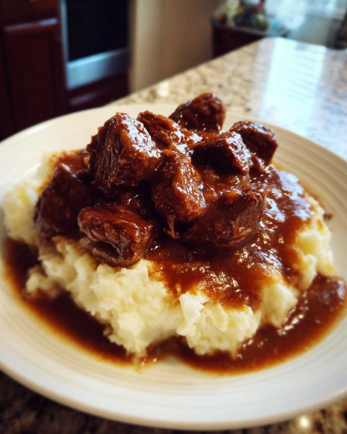 A plate of tender crockpot beef tips smothered in rich gravy served over creamy mashed potatoes.