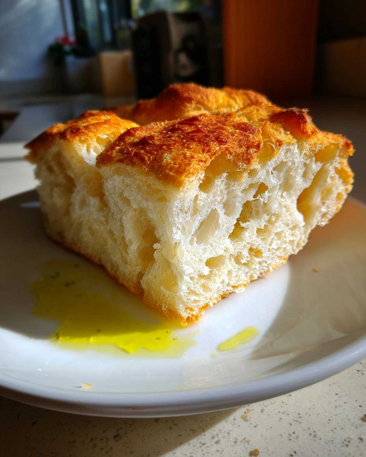 A thick slice of crusty Italian bread with an open crumb served next to a pool of green olive oil.