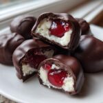 Close-up of homemade chocolate covered cherries, showing the creamy white filling and bright red cherry inside.