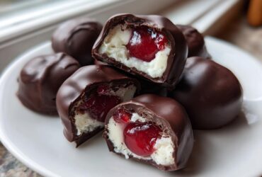 Close-up of homemade chocolate covered cherries, showing the creamy white filling and bright red cherry inside.