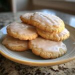 A close-up stack of soft, round sugar cookies topped with a thin layer of white glaze.