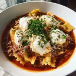 A close-up of a hearty bowl of instant pot lasagna soup featuring pasta, rich meat sauce, and dollops of ricotta cheese topped with parsley.