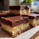 Several rich, layered no bake peanut butter bars topped with a thick layer of smooth chocolate ganache.