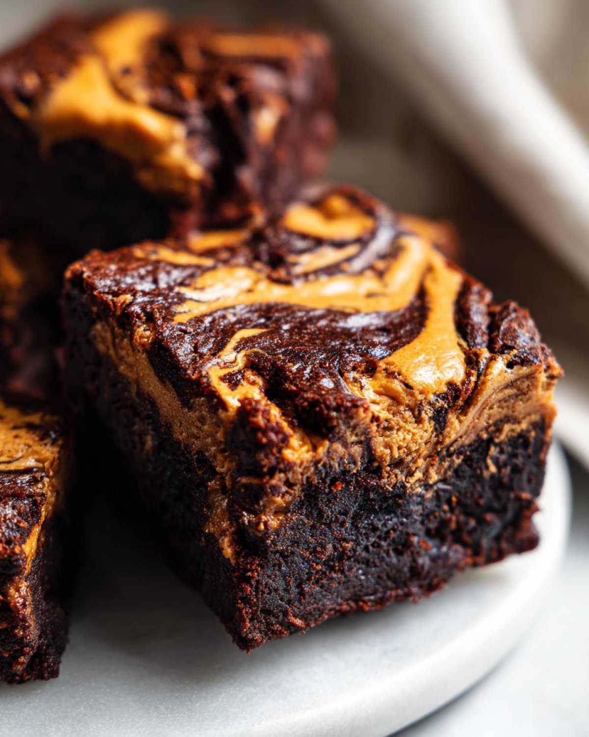 A close-up of a rich, fudgy square of peanut butter swirl brownies showing the dark chocolate base and golden peanut butter topping.