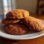 A stack of four soft, cinnamon-sugar coated pumpkin snickerdoodle cookies resting on a white plate.