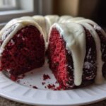 A slice cut from a vibrant red velvet bundt cake topped with thick white cream cheese glaze.