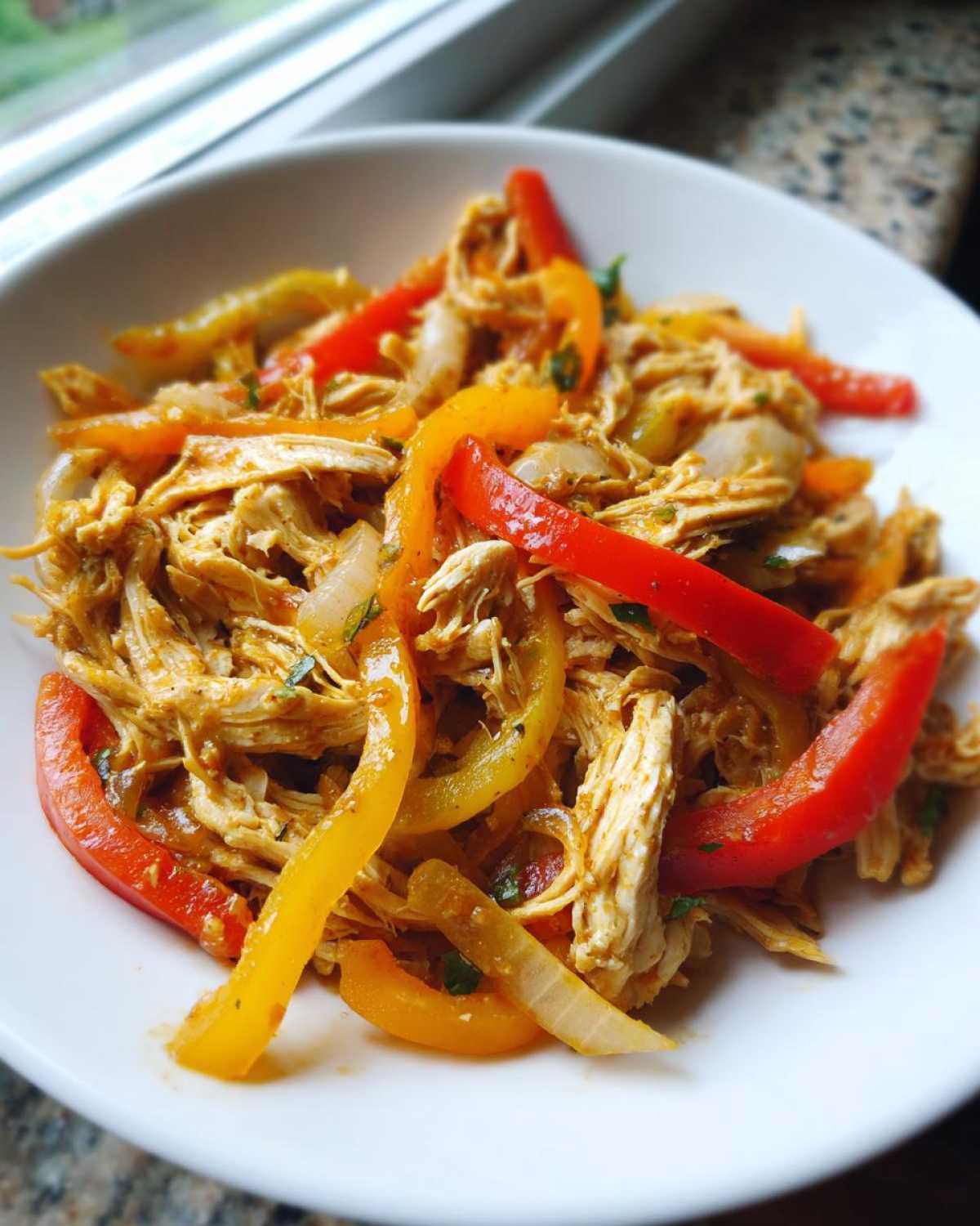 Close-up of shredded chicken mixed with colorful bell peppers and onions, ready for crockpot chicken fajitas.