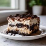 Close-up of a layered slice of dirt cake featuring alternating layers of cream and dark chocolate cookie crumbs.