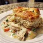 Close-up of a serving of slow cooker chicken pot pie with creamy filling, vegetables, and a flaky biscuit topping.