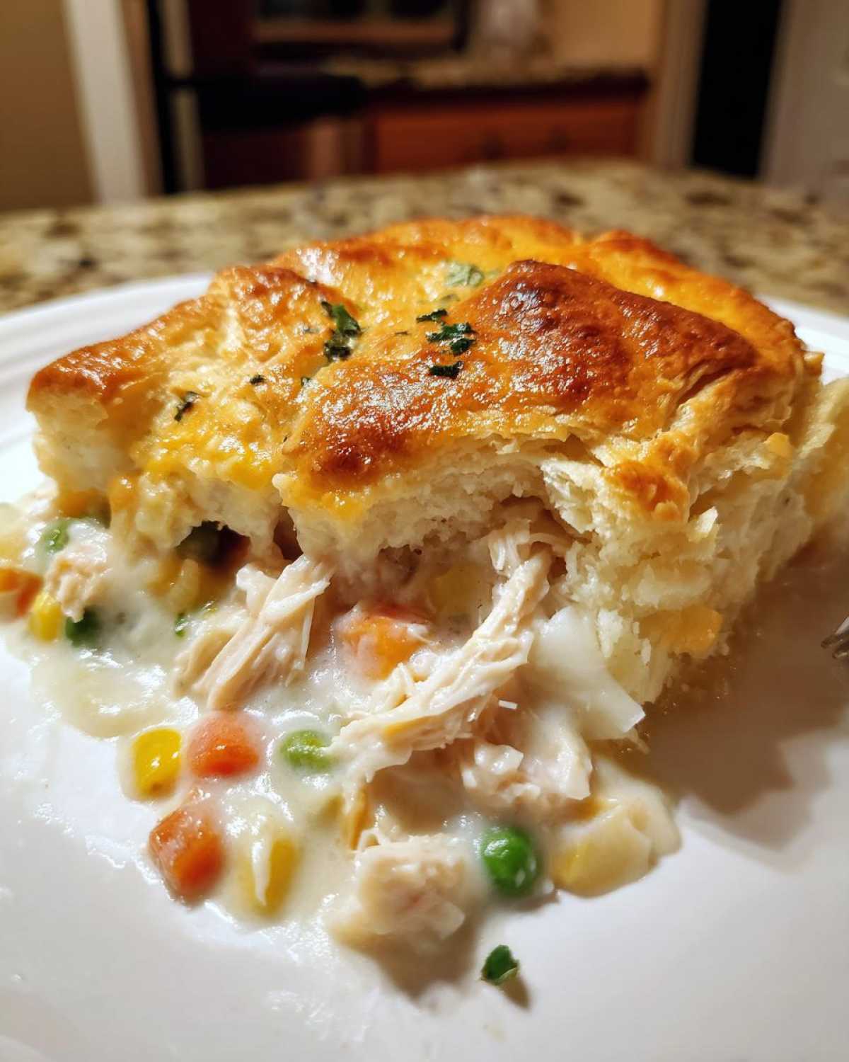 A serving of creamy slow cooker chicken pot pie showing shredded chicken, peas, carrots, and a golden, flaky crust.