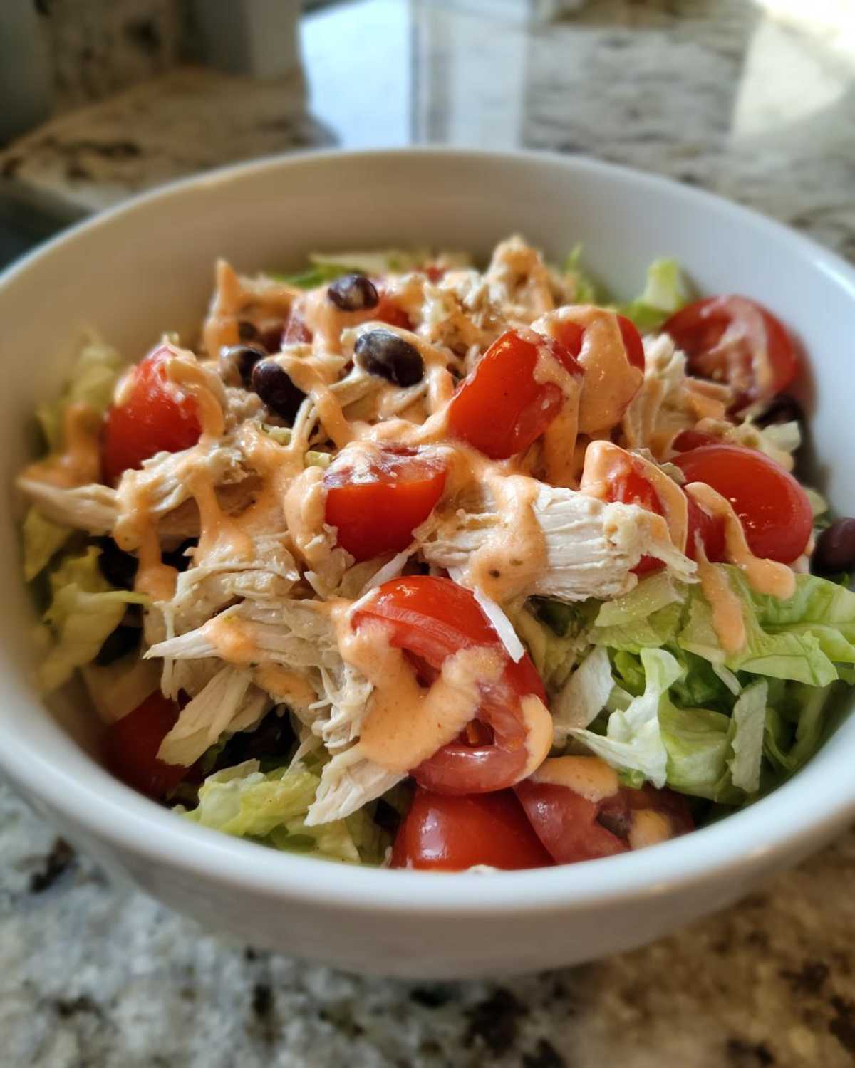Close-up of a vibrant southwest chicken salad featuring shredded chicken, cherry tomatoes, black beans, and creamy dressing.
