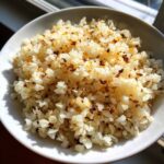 Close-up of fluffy, slightly browned cauliflower rice served in a white bowl, ready to eat.
