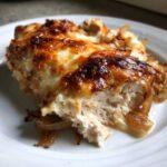 A close-up, tasty shot of a serving of french onion chicken topped with melted, browned cheese and caramelized onions.