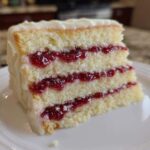 Close-up of a delicious slice of white chocolate raspberry cake showing three layers of white cake and raspberry filling.
