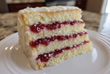 Close-up of a delicious slice of white chocolate raspberry cake showing three layers of white cake and raspberry filling.