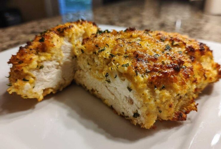 Cross-section of juicy baked ranch chicken showing the white interior and golden, herbed crust.