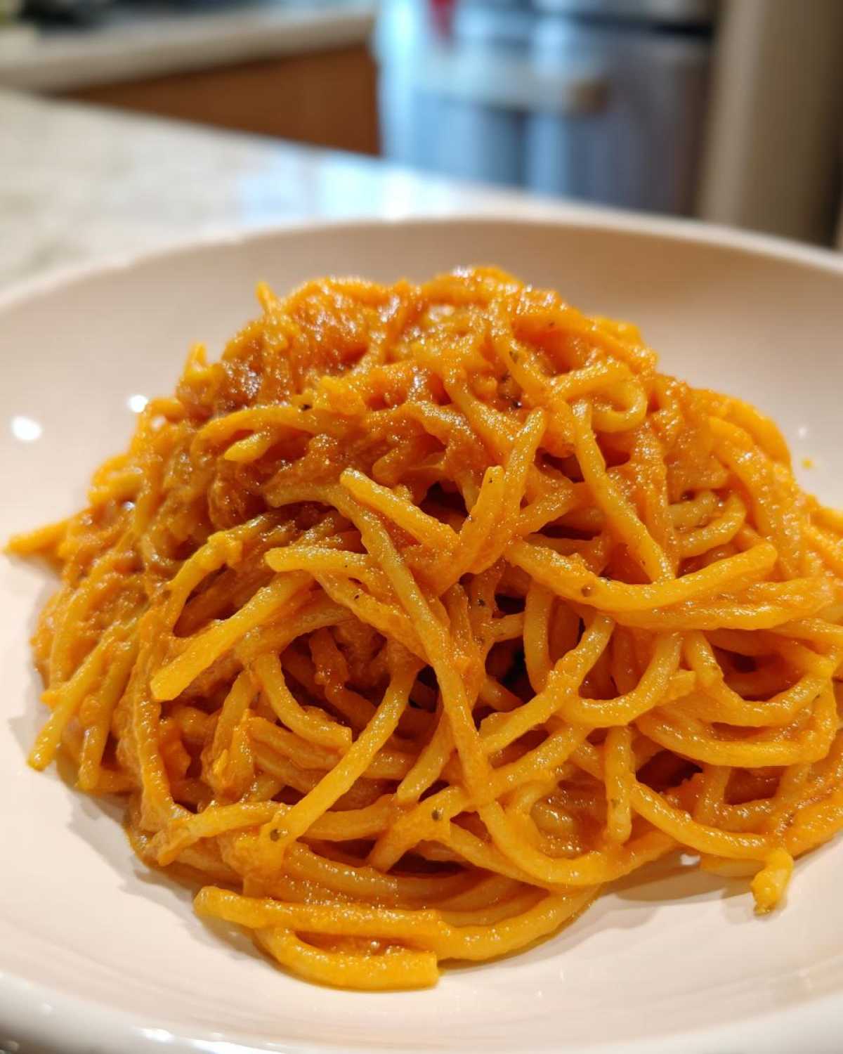 Close-up of spaghetti noodles generously coated in a creamy, orange butternut squash pasta sauce.