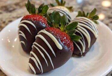 Four beautiful chocolate covered strawberries drizzled with white chocolate, ready to eat.