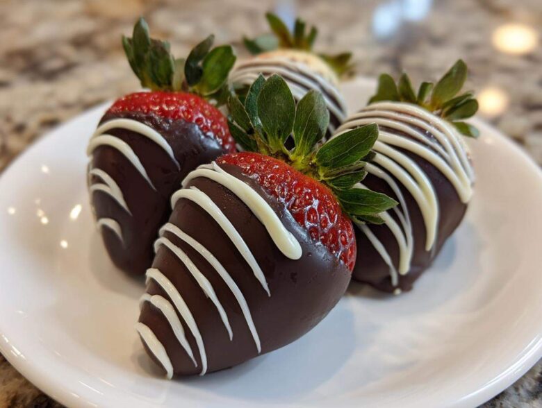 Four beautiful chocolate covered strawberries drizzled with white chocolate, ready to eat.