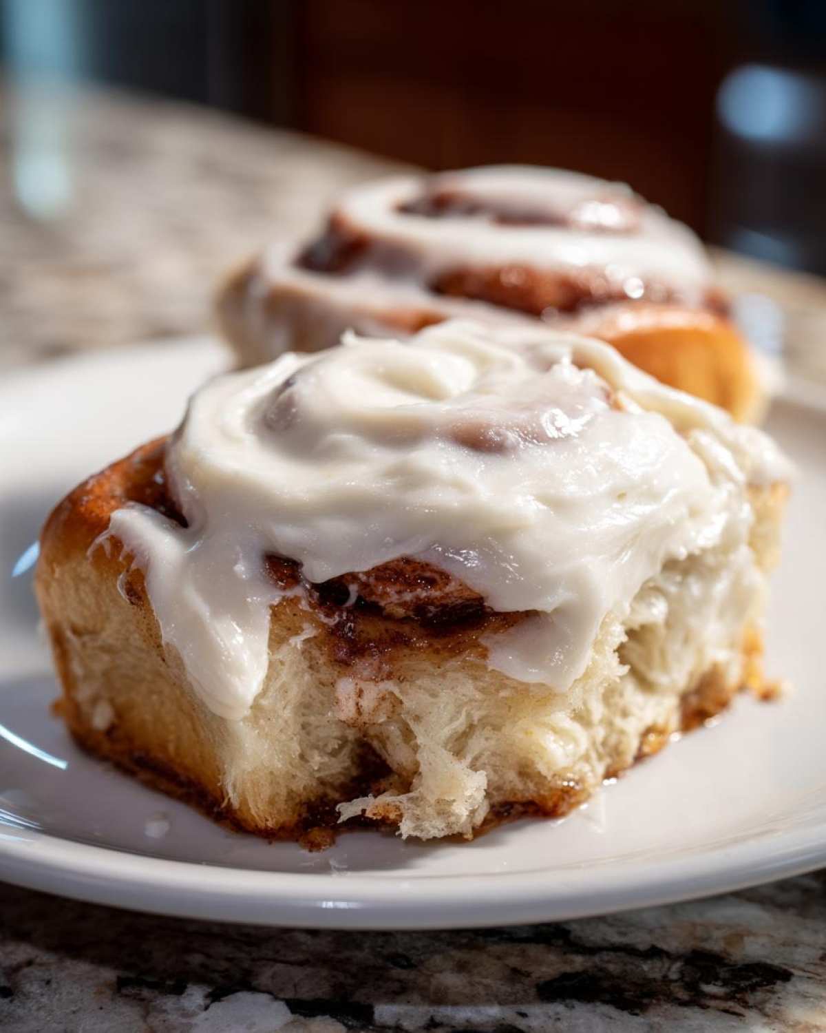 Close-up of a soft cinnamon roll generously topped with thick Copycat Cinnabon Cream Cheese Frosting.