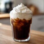 A tall glass of iced coffee topped generously with whipped Copycat Starbucks Vanilla Sweet Cream Cold Foam.
