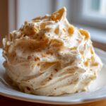 A generous swirl of fluffy Copycat Texas Roadhouse Cinnamon Honey Butter sprinkled with cinnamon on a white plate.