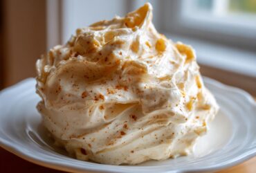 A generous swirl of fluffy Copycat Texas Roadhouse Cinnamon Honey Butter sprinkled with cinnamon on a white plate.