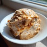 A scoop of fluffy, light brown Copycat Texas Roadhouse Cinnamon Honey Butter served in a white bowl.
