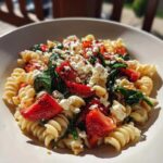 Close-up of a bowl of Easy Strawberry Spinach Pasta Salad with feta cheese and rotini pasta.
