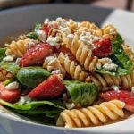 Close-up of Easy Strawberry Spinach Pasta Salad with Feta, featuring rotini pasta, fresh strawberries, spinach, and crumbled cheese.