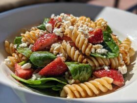 Close-up of Easy Strawberry Spinach Pasta Salad with Feta, featuring rotini pasta, fresh strawberries, spinach, and crumbled cheese.