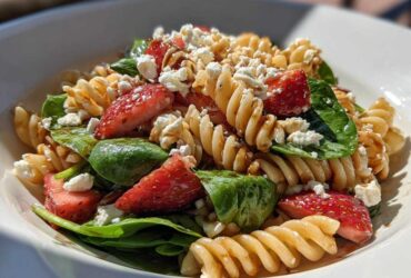 Close-up of Easy Strawberry Spinach Pasta Salad with Feta, featuring rotini pasta, fresh strawberries, spinach, and crumbled cheese.