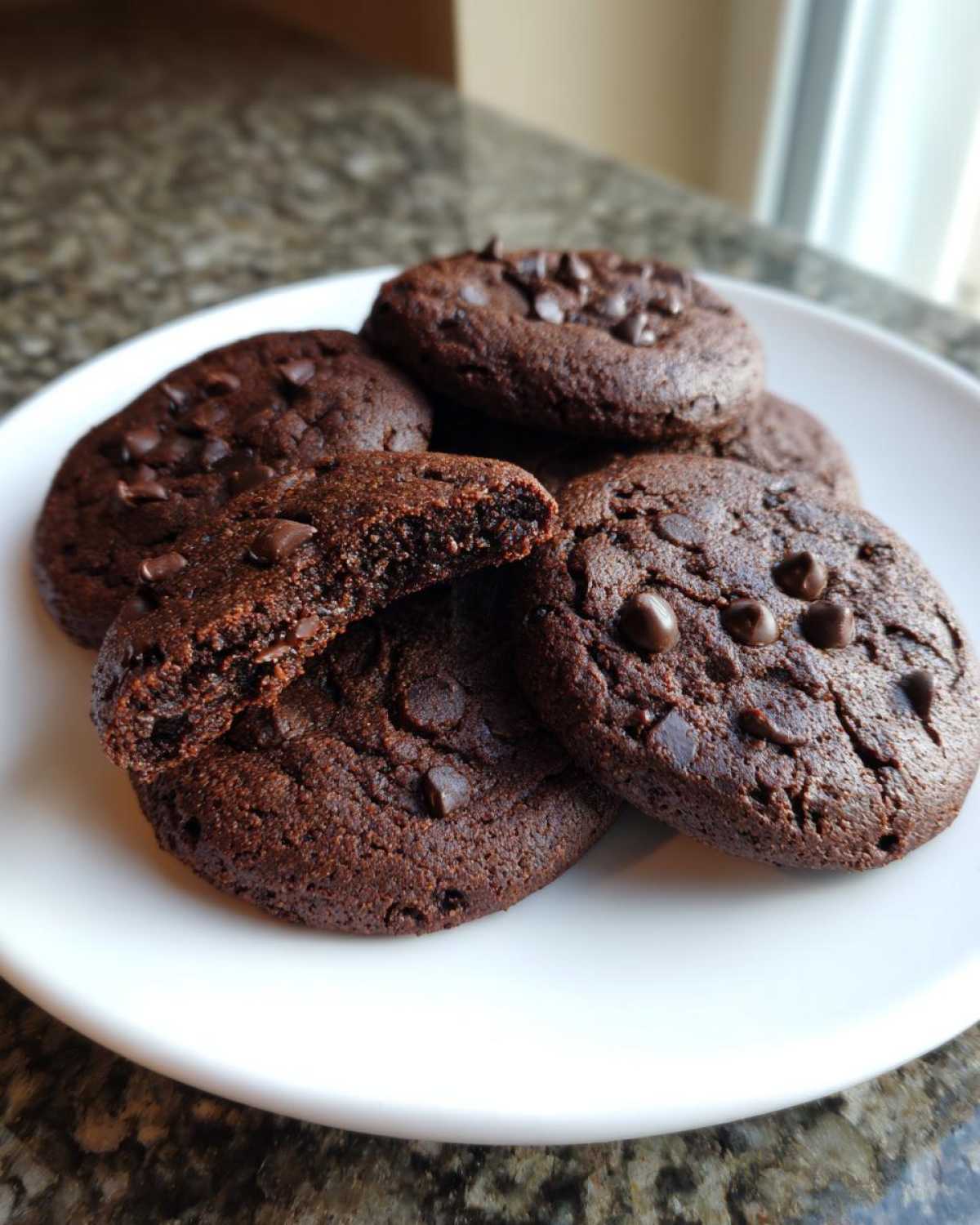 A stack of rich, dark Gluten-Free Chocolate Mint Cookies, one broken in half showing the soft interior.