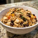 A close-up of Instant Pot Chicken Burrito Bowls with Brown Rice, shredded chicken, black beans, and peppers in a white bowl.