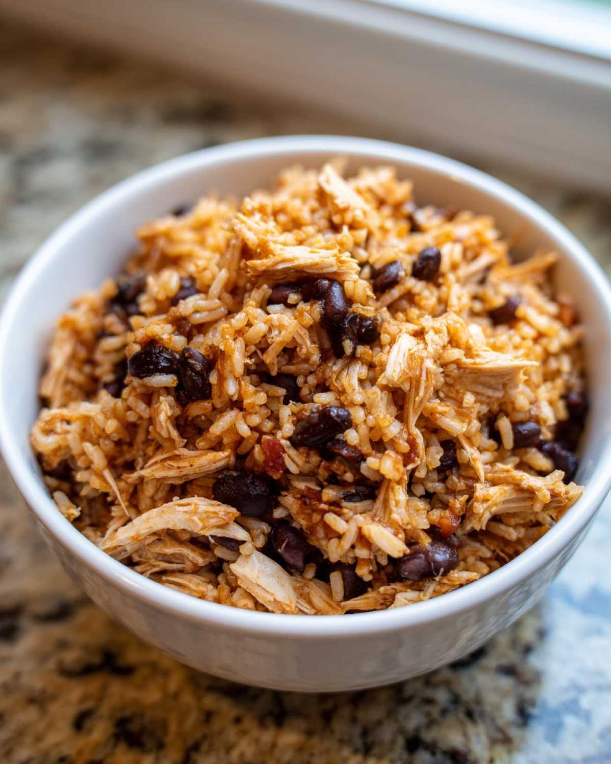 Close-up of shredded chicken mixed with seasoned brown rice and black beans, a key component for Instant Pot Chicken Burrito Bowls.