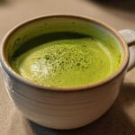 Close-up of a vibrant green, creamy soup, resembling Instant Pot Creamy Asparagus Soup, in a rustic white mug.