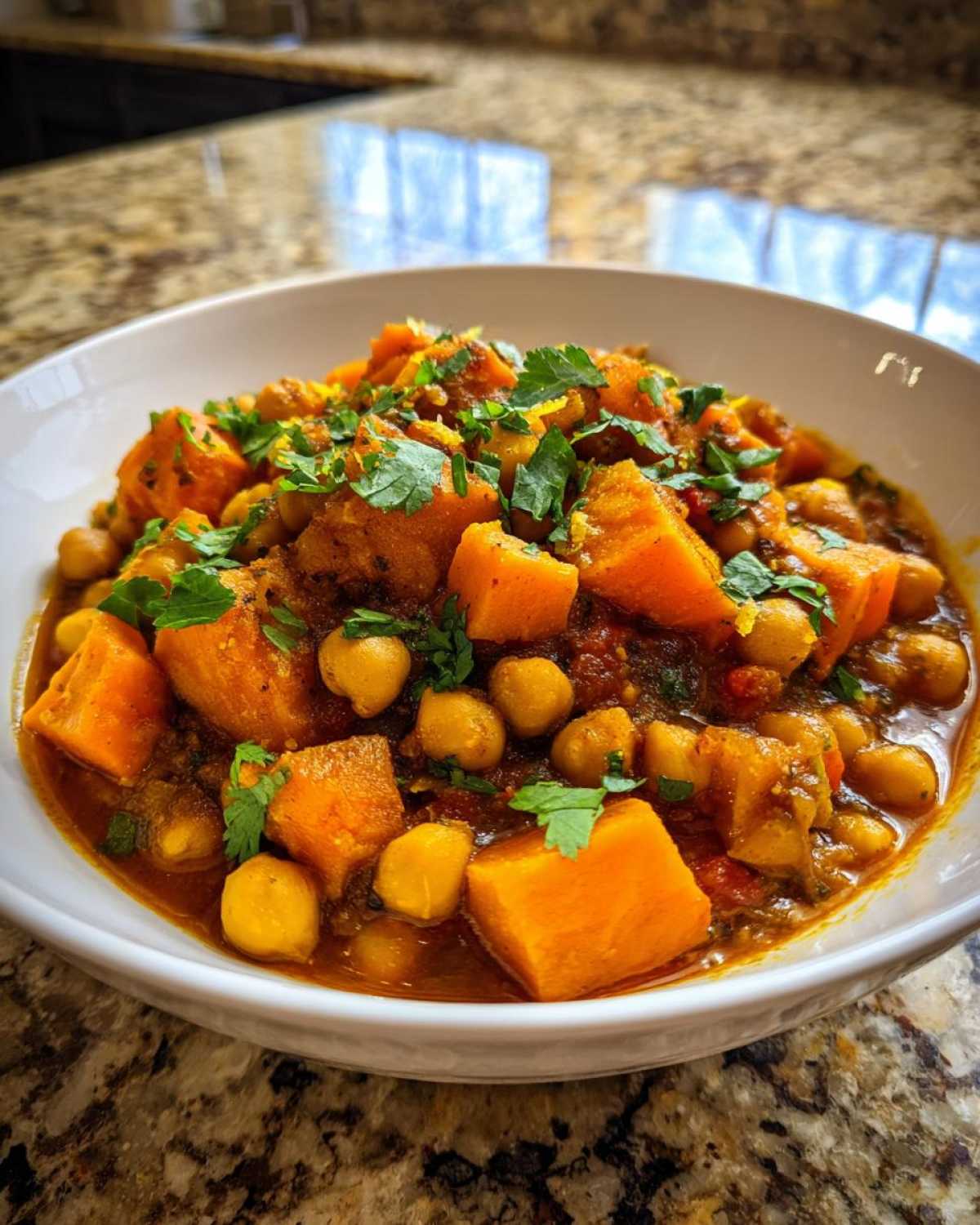 A close-up of Instant Pot Moroccan Chickpea Stew with large chunks of sweet potato and chickpeas in a rich sauce, topped with fresh cilantro.
