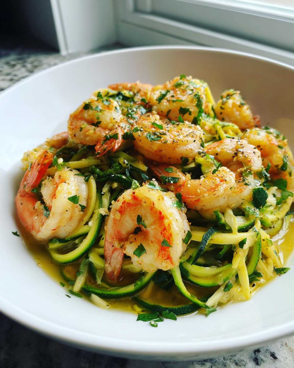 Close-up of Keto Shrimp Scampi Zucchini Noodles topped with large shrimp and fresh parsley.