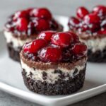 Close-up of a No-Bake Chocolate Cherry Cheesecake Cup with a dark crust and bright cherry topping.