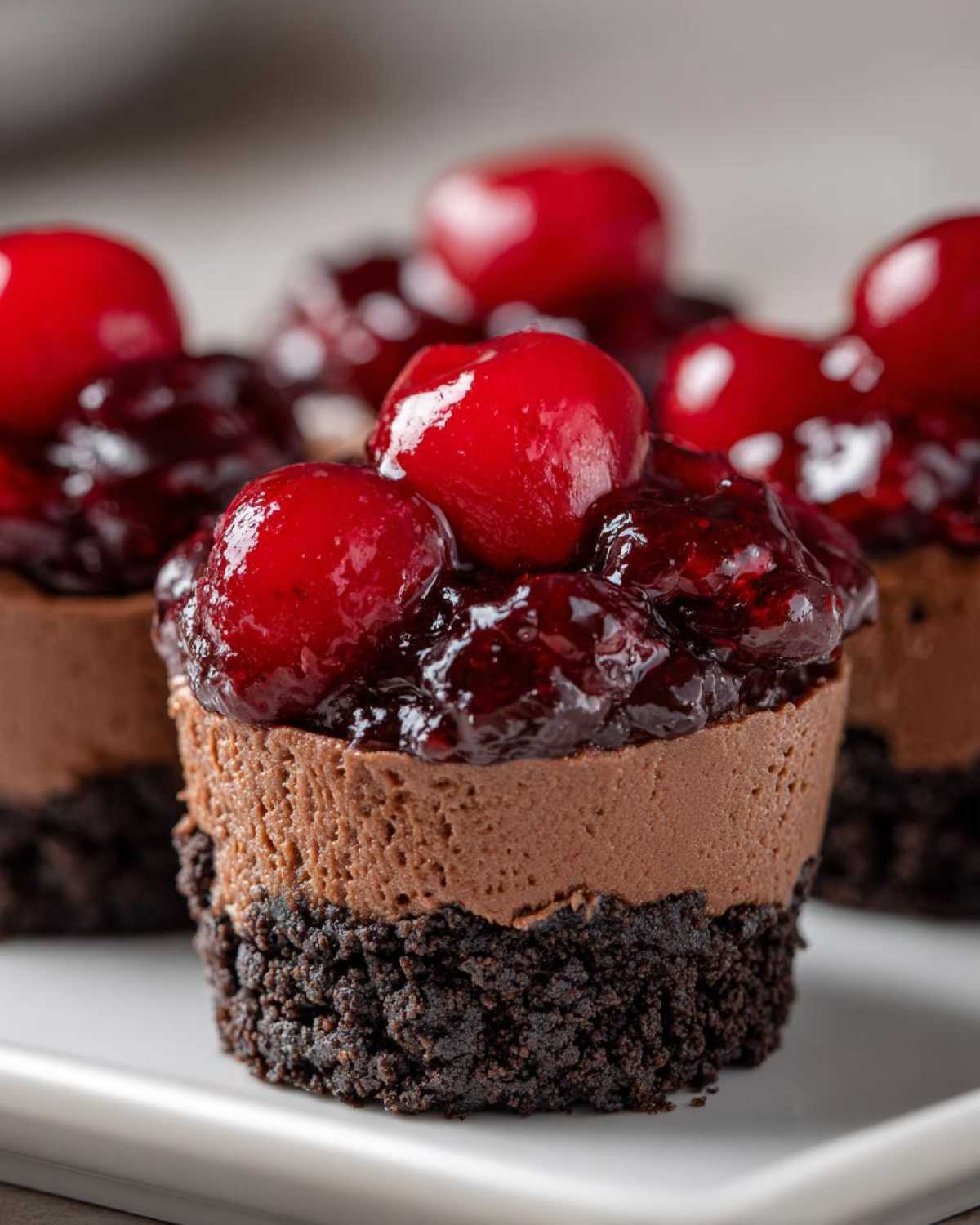 Close-up of a No-Bake Chocolate Cherry Cheesecake Cup with a dark chocolate crust and cherry topping.