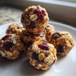 A stack of homemade No-Bake Lemon Blueberry Energy Bites made with oats and dried fruit on a white plate.