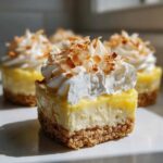 Cross-section of a No-Bake Lemon Coconut Cream Pie Cup showing graham cracker crust, lemon filling, and whipped topping with toasted coconut.