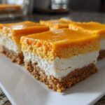 Close-up of several No-Bake Orange Creamsicle Cheesecake Bars showing graham cracker crust, white filling, and orange topping.