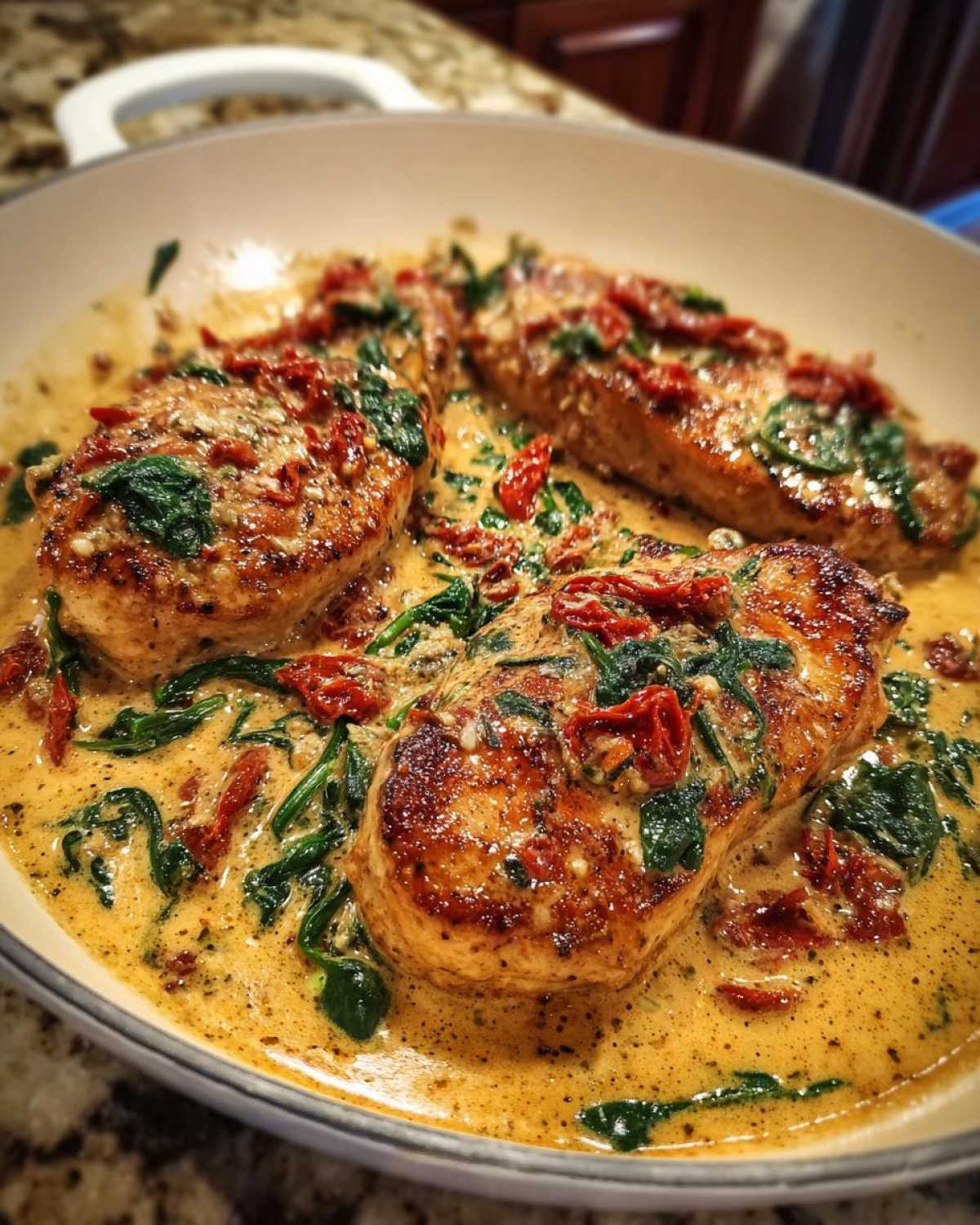 Three seared turkey cutlets swimming in a creamy garlic butter sauce with spinach and sun-dried tomatoes, the One-Pan Creamy Garlic Butter Turkey Cutlets.