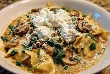 A close-up of One-Pot Creamy Spinach Mushroom Lasagna Soup topped with ricotta and parmesan cheese.